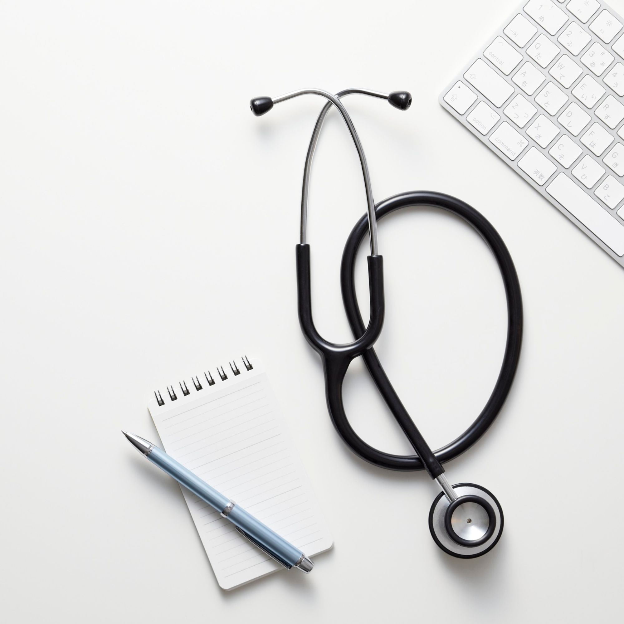 Image of a stethscope and pad of paper on a gray background